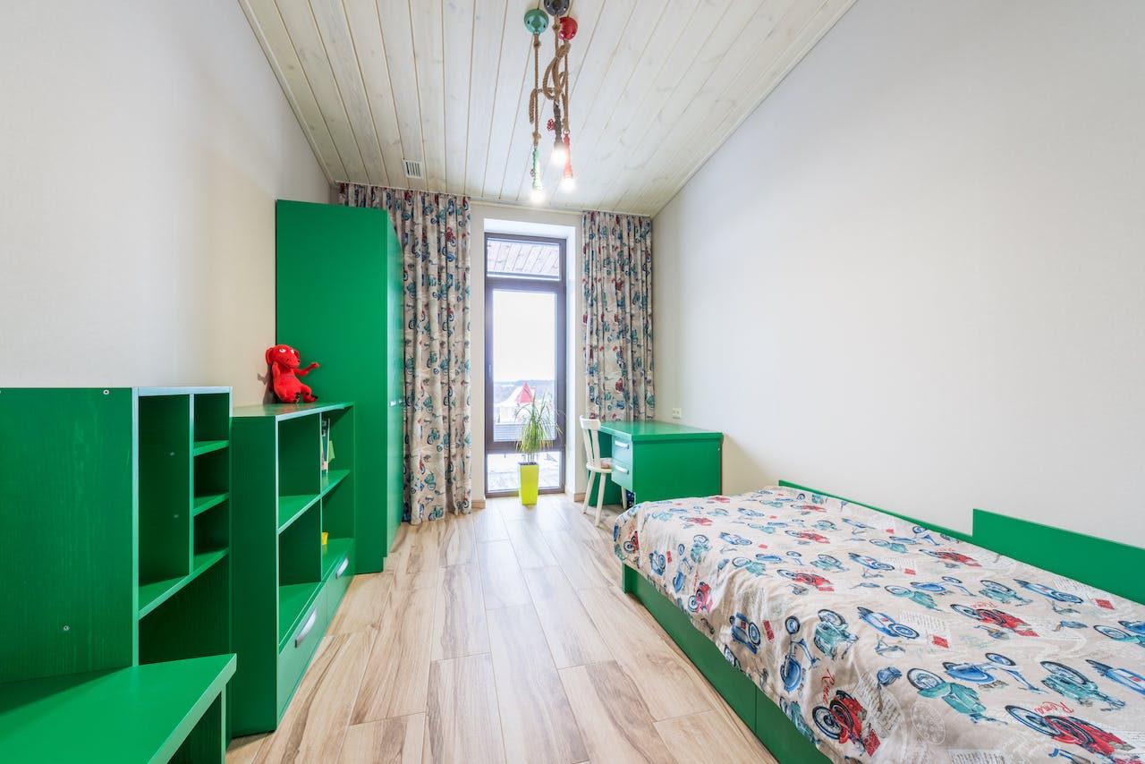 Na obrazku widoczny jest przytulny pokój dla chłopca, urządzony w stylu chłopięcym z kolorowymi dekoracjami i funkcjonalnymi meblami