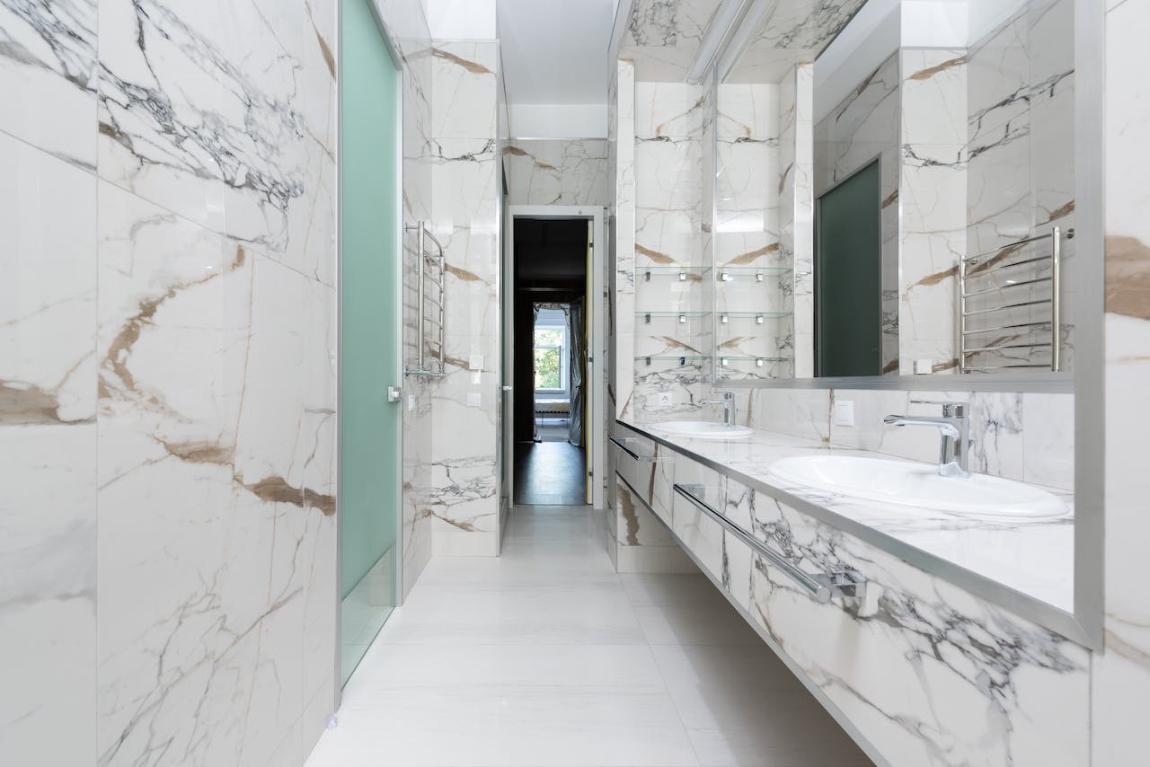 Na obrazku widoczna jest luksusowa marmurowa łazienka, emanująca elegancją i prestiżem dzięki swoim wykwintnym detalom i perfekcyjnemu połączeniu klasycznego wzornictwa z nowoczesnym stylem