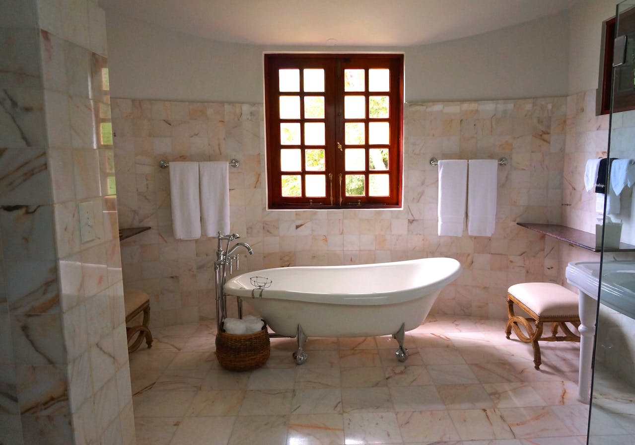 Na obrazku widoczna jest elegancka biała łazienka z subtelnymi elementami drewna, tworząca harmonijną i naturalną atmosferę